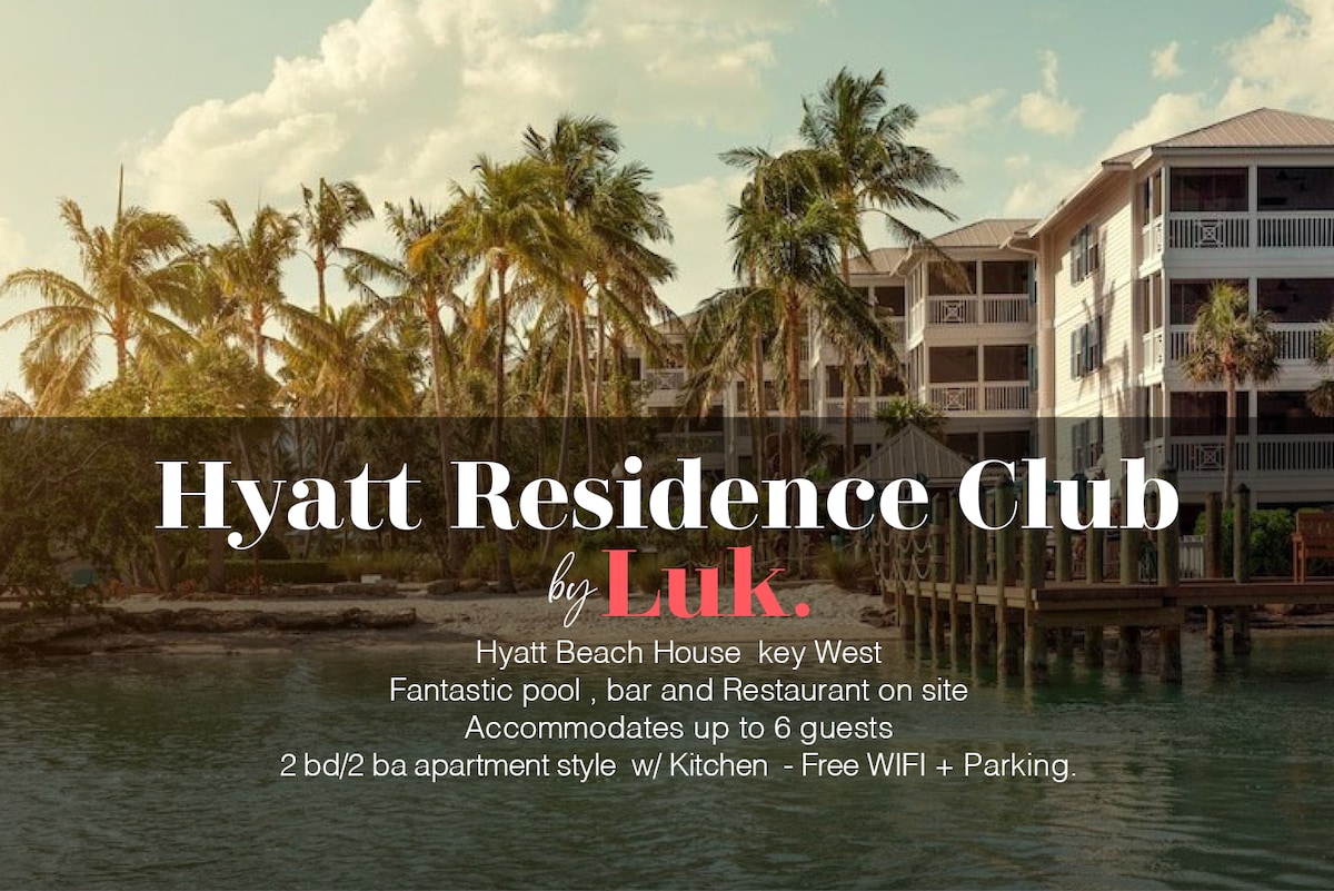 The image captures the serene exterior of the Hyatt Residence Club, surrounded by lush palm trees overlooking the water. The building features an inviting pool area, bar, and restaurant on-site, providing a welcoming atmosphere for guests.
