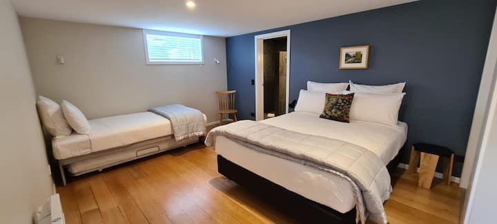 غرفة نوم منفصلة بسرير ملكي وسرير فردي كبير مع ترندلر واحد تحته لإنشاء أسرّة لـ 4 أشخاص. يؤدي الباب إلى الحمام المبلط بالكامل.