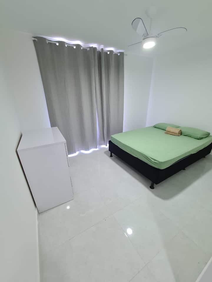 Apartman u spavaćoj sobi s komodom za odjeću za zamračivanje i bračnim krevetom.
