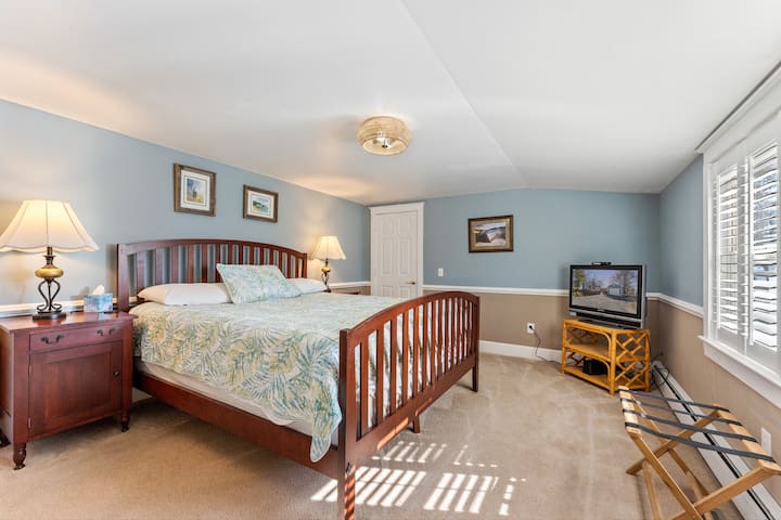 Renovated master bedroom with a king bed and portable crib.
