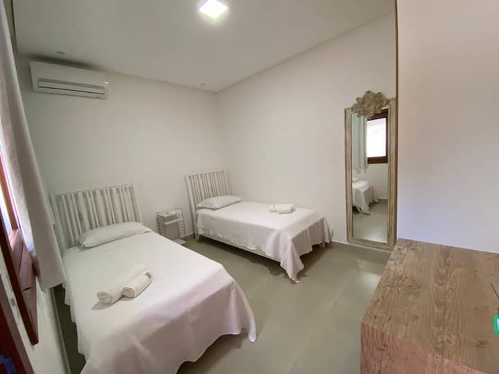 غرفة نوم في الطابق الأرضي ، مع مكيف هواء ، وسريرين فرديين ، ومراتب أورتوبون سبرينغ ، ومرآة ، وخزانة مع بابين ، ومكتب ، ورف ملابس.