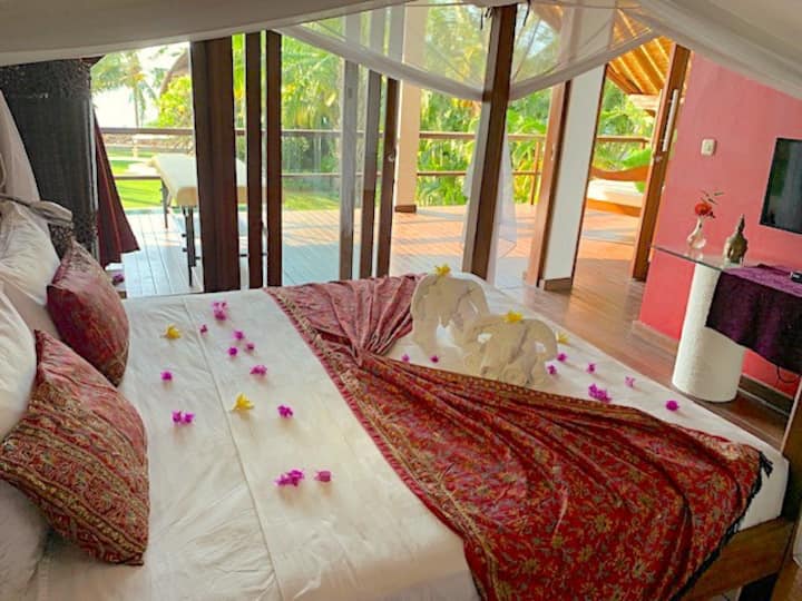 All the bedrooms have attractive views, king size mattresses, A/C, a wardrobe, dresser, safe box & en suite private bathroom w. w/c & shower. This Master has a TV, tub and a balcony with a massage table and an upholstered Balinese sofa bench (RHS)