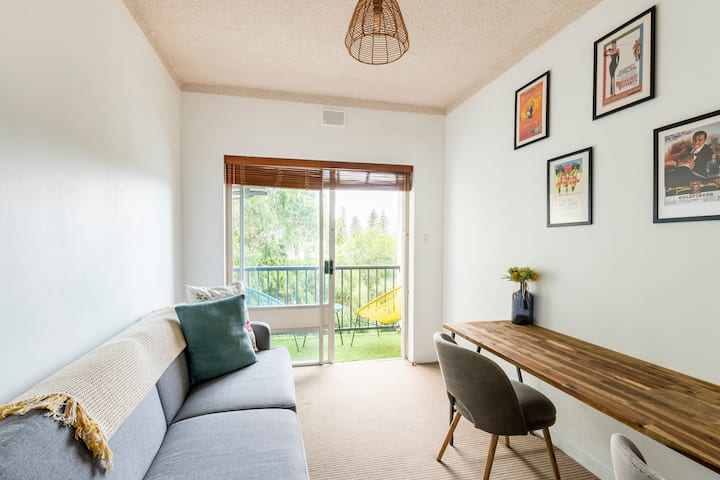 Office with large desk, sofa bed and adjoining balcony—natural light aplenty