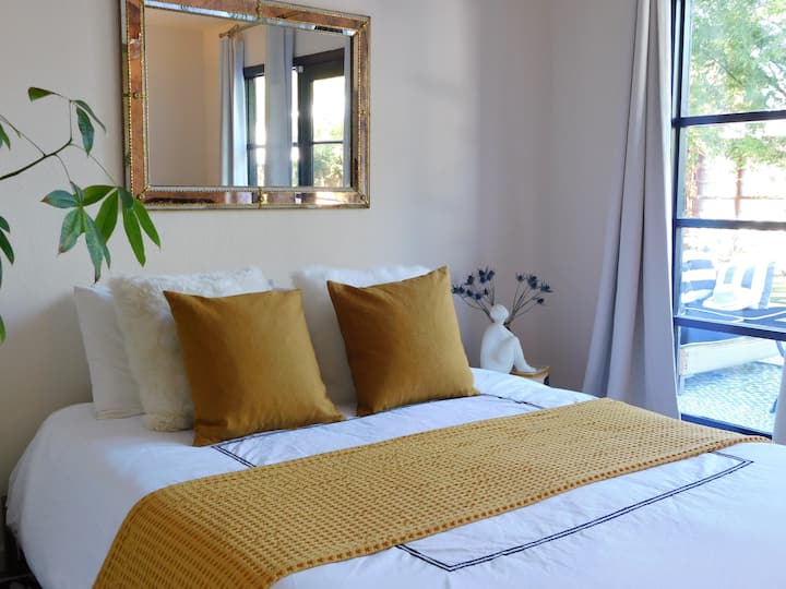 Segundo dormitorio con ventanas del piso al techo y una vista del patio trasero y la piscina profunda. 