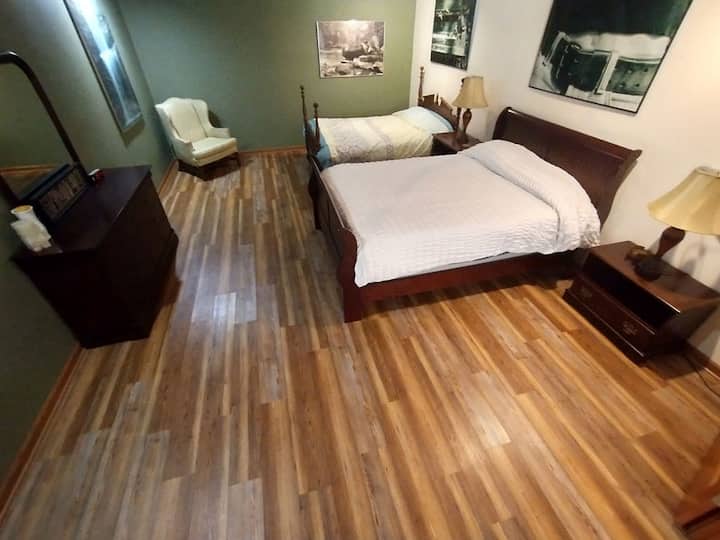 The main bedroom has a 2 Queen beds, a dresser, chair, and bed side tables. 