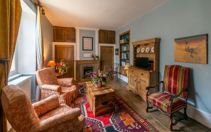 This snug sitting area, adorned with traditional textiles and warm wooden accents, provides a homely space to unwind with a selection of books and entertainment.