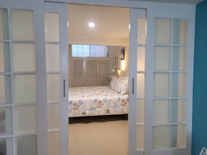 غرفة نوم أنيقة بسرير بحجم كينج وحمام كامل وتكييف هواء ومروحة سقف.