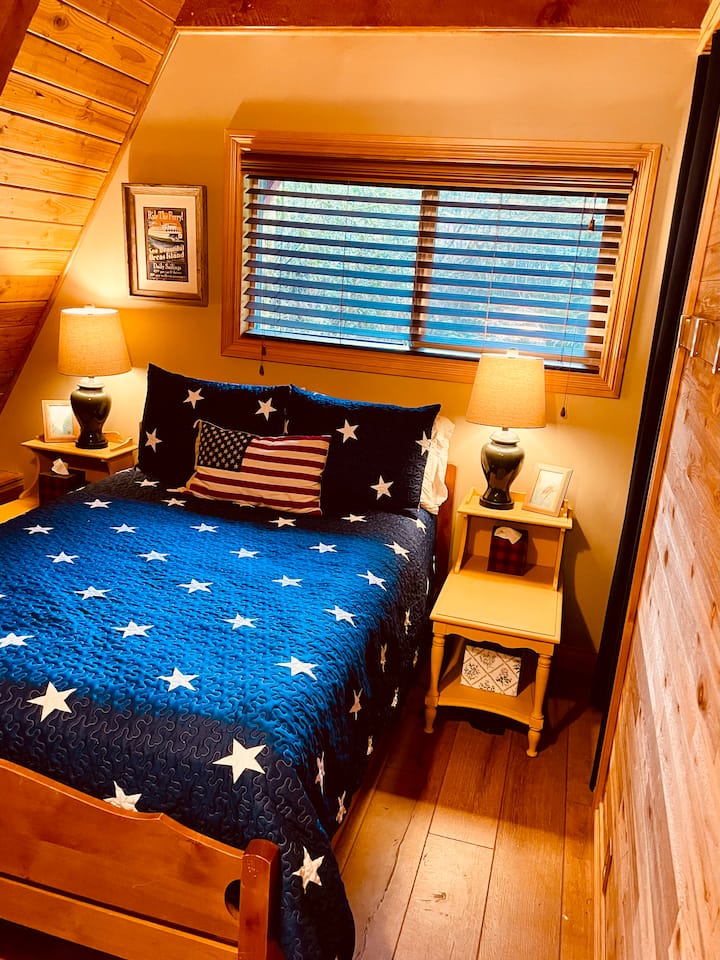 Dormitorio en el piso principal con cama de tamaño completo y cortina para mayor privacidad.