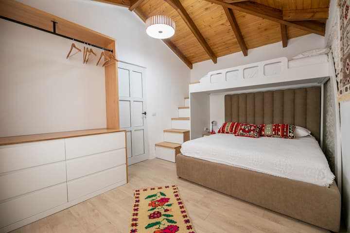 חדר השינה השני מרוהט במיטה זוגית ומיטת קומתיים אחת הממוקמת מעליו. 