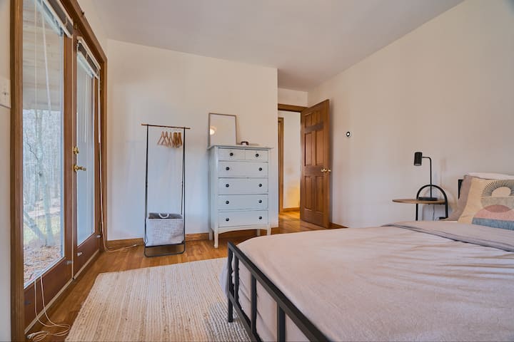 卧室位于一楼，标准双人床，房间内光线充足，门在纱门廊上打开。