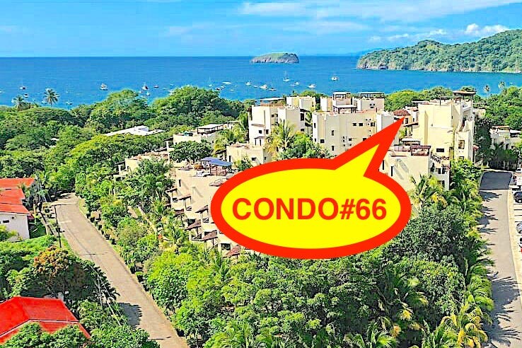 An aerial view of the gated community showcases lush greenery and the ocean in the background. The condominium building is visible, with a vibrant red label highlighting 'CONDO#66.' Boats can be seen in the water, with hills framing the serene coastal landscape.