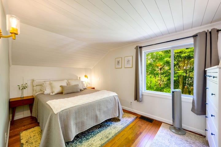 Un dormitorio tranquilo con una cama tamaño queen y vistas a los bosques circundantes.