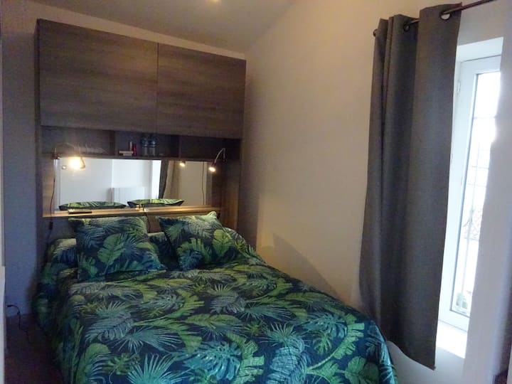 Pequeña habitación con cama de 140  ventana, tv y  aire acondicionado en el pasillo de la parte de la noche