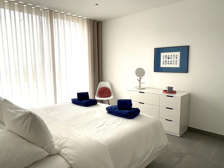 Dormitorio principal sereno con grandes ventanas.