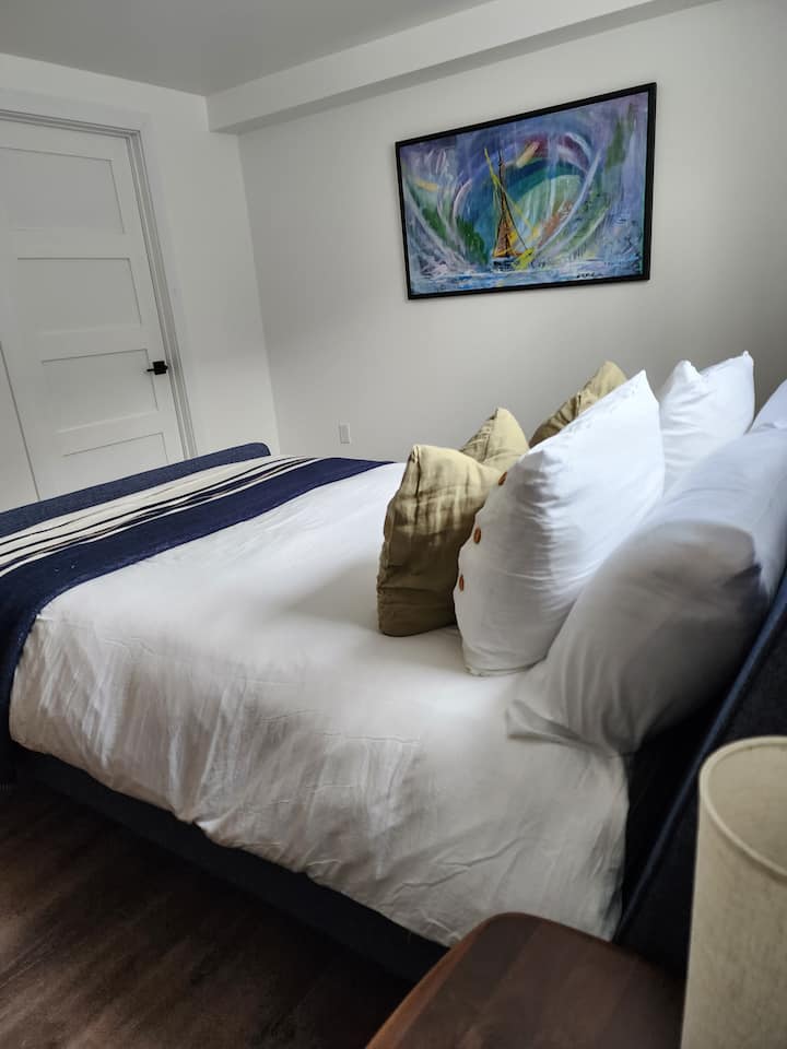 Basement bedroom with queen size bed and dresser.