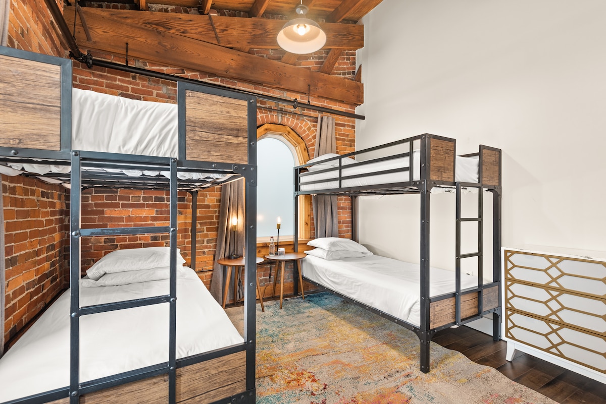 ¡Una habitación de literas nunca se ha parecido tan cálida y acogedora! Se proporcionan cortinas negras para cada una de las tres hermosas ventanas arqueadas. 