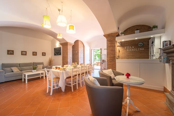 Sebule iliyo na eneo janja la kufanyia kazi lenye printa na dawati la Wi-Fi, kitanda cha sofa, eneo la moto lenye eneo la kukaa, baa ya uaminifu iliyo na mvinyo wa mvinyo wa eneo husika na vinywaji baridi