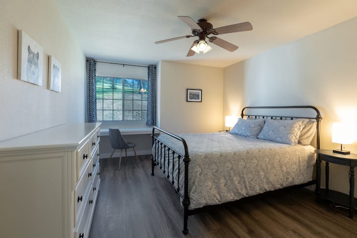 Chumba cha kulala kilicho na kitanda cha Queen, dawati lililojengwa dirishani. Meza za pembeni, taa za kusoma, feni ya dari na kabati la kuingia.