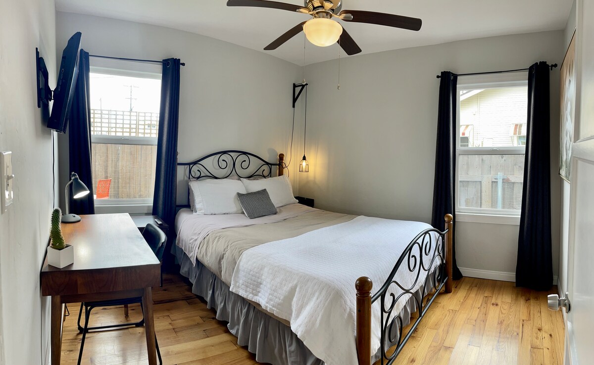 Back bedroom.  Queen bed, small desk, smart TV.  Closet with drawers and hangers.