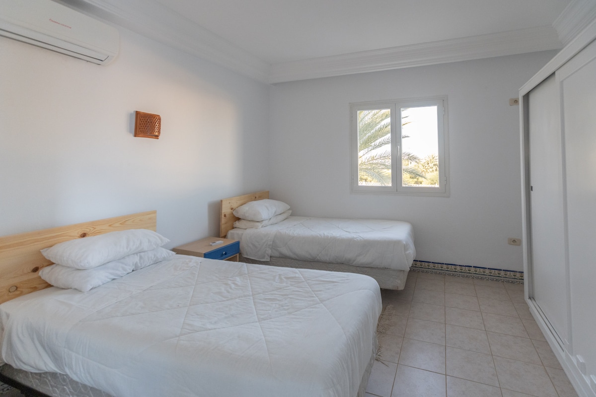 Slaapkamer met airconditioning, comfortabel bed, kwaliteitslinnen en opbergruimte. Rustige sfeer en decor geïnspireerd door Djerba voor totale rust.