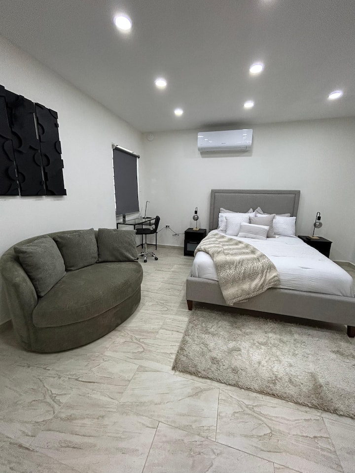 Grande chambre avec lit Queen Size, canapé et bureau pour travailler.
