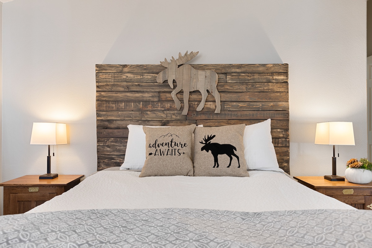 Chumba kikuu cha kulala cha Moose Manor kilicho na mapambo kamili ya Moose na matandiko ya kustarehesha.