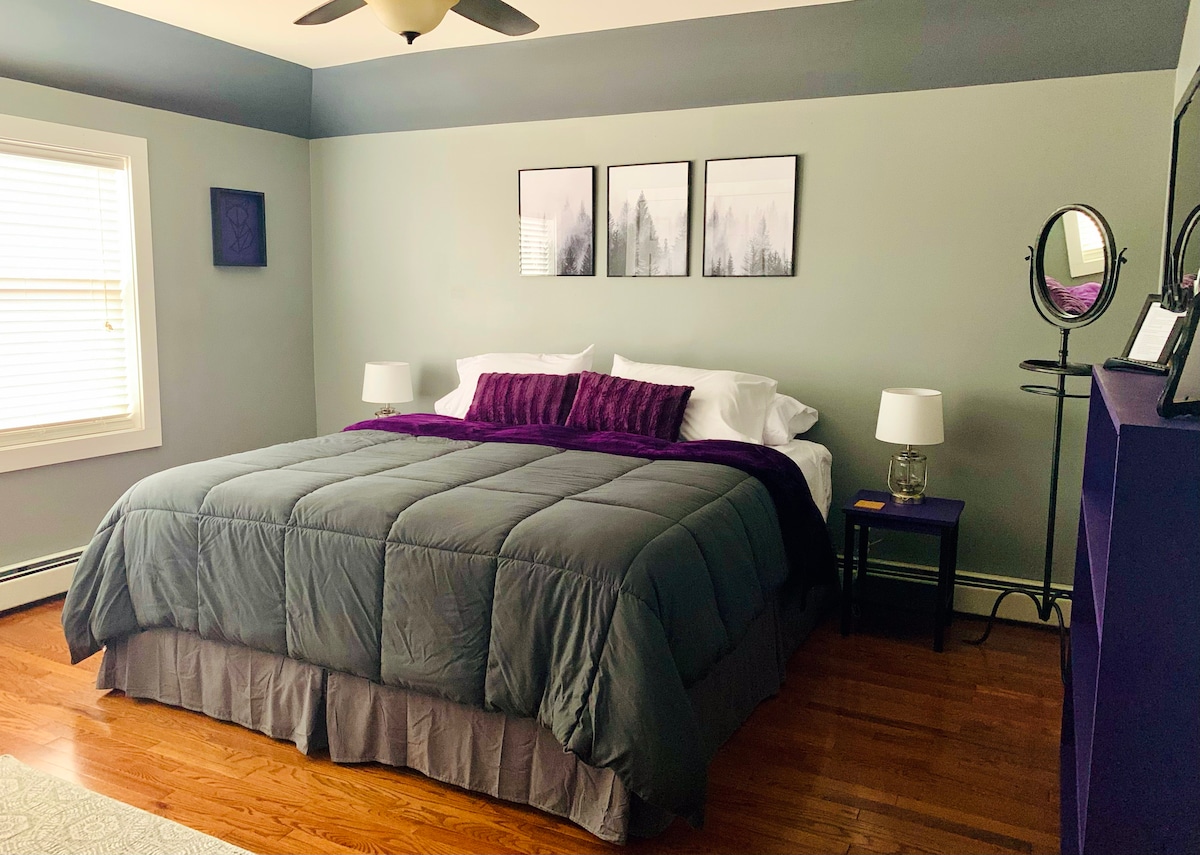 La habitación Foggy Forest incluye una cama tamaño king y decoración morada pintada a mano, así como una ventana gigante y un hermoso espejo antiguo.