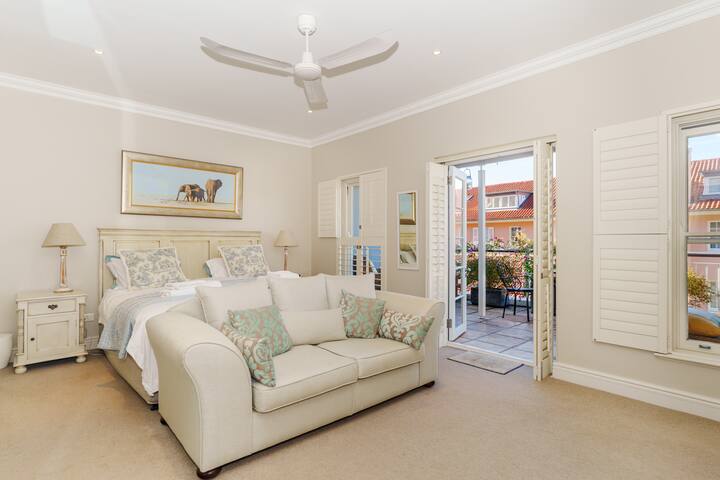 Amplio y lujoso dormitorio principal con cama tamaño king y sofá, con baño privado con bañera y ducha y amplio espacio en el armario.