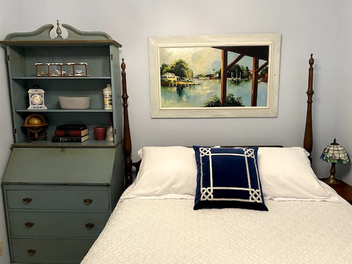 Queen Size Bed and drop down desk for desigated work area. Painting is a view of the lagoons in the 1970’s.