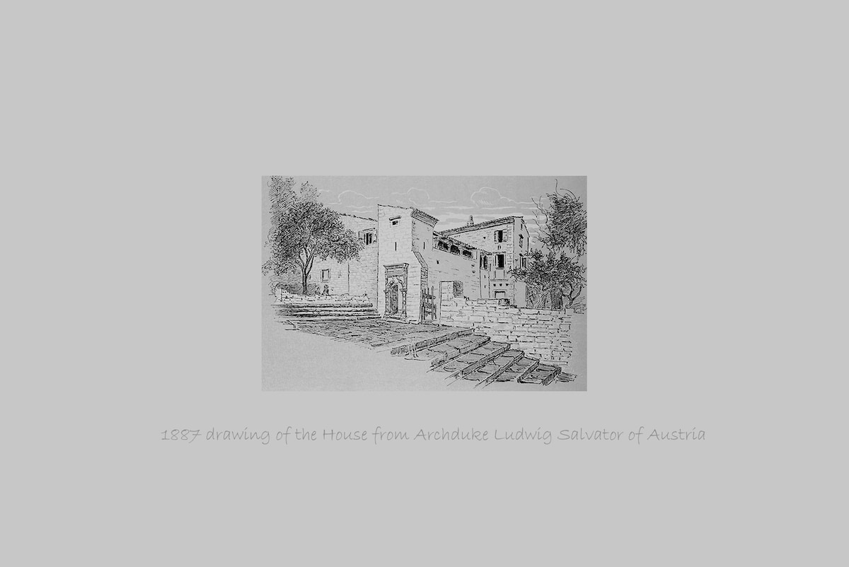 An 1887 drawing depicts the house, showcasing traditional architectural details. Surrounding it are landscaped areas featuring trees and pathways, with stone steps leading up to the entrance, offering a glimpse of the property’s historical significance.