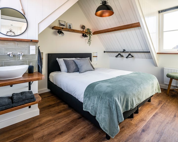 Katika chumba hiki cha kulala kuna kitanda cha watu wawili, kinaning 'inia televisheni janja, bakuli la kufulia la kujitegemea na uchaga mzuri wa nguo.