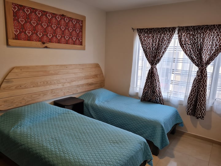 Bedroom with 2 single beds, fan and closet.