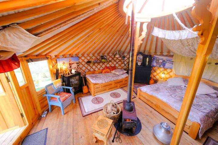 Overzicht van de linkerkant van de yurt (zithoekje, whiskey kastje, slaapbank, kledingkast/servies kast, kachel).