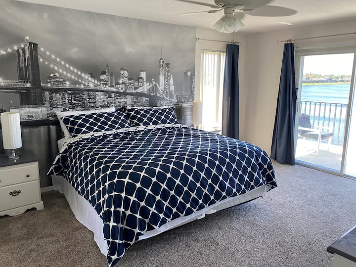 Extra veľká hlavná spálňa na poschodí, vybavená inteligentnou televíziou na sledovanie všetkých streamovacích služieb a balkónom s výhľadom na jazero.