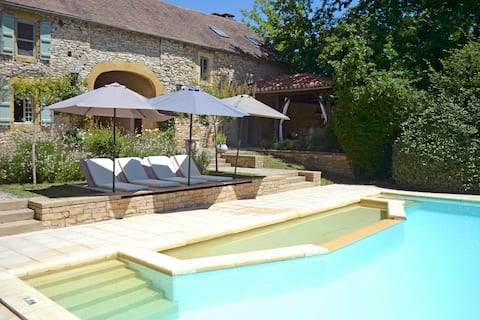 Stone barn with a swimming pool and lake.