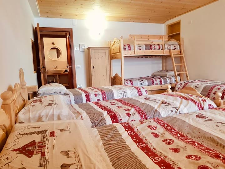 Chambre avec des lits superposés et des lits simples, salle de bain avec aspirateur. 