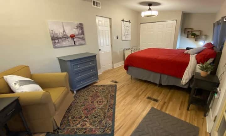 رئيسي واسع ومريح مع سرير بمقاس كينج وإمكانية الوصول إلى السطح الخارجي ومنطقة جلوس ومساحة عمل مخصصة مع مكتب في كوبي بعيد.