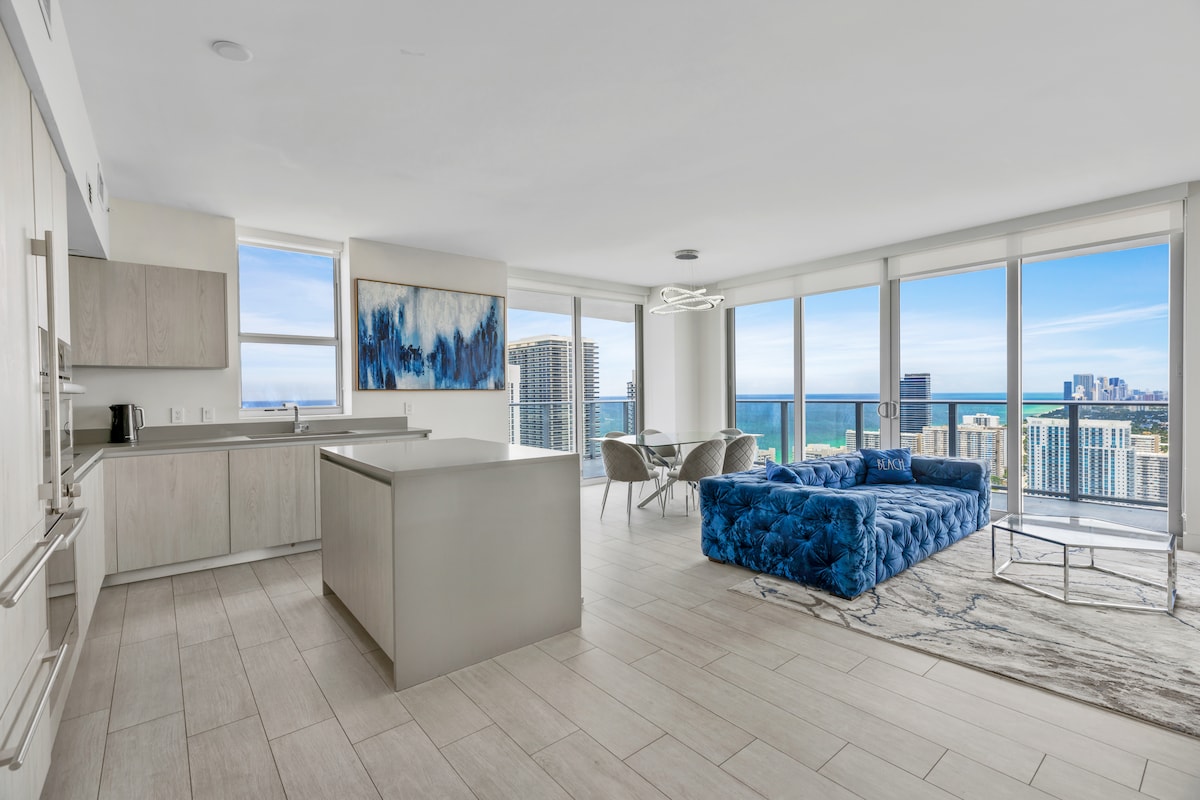 הסלון הפתוח והמואר כולל חלונות מהרצפה עד התקרה עם נוף מרהיב לעיר ולים. המטבח המודרני כולל אי גדול עם מקומות ישיבה רבים, מושלם לארוחות או למנוחה תוך כדי נוף.