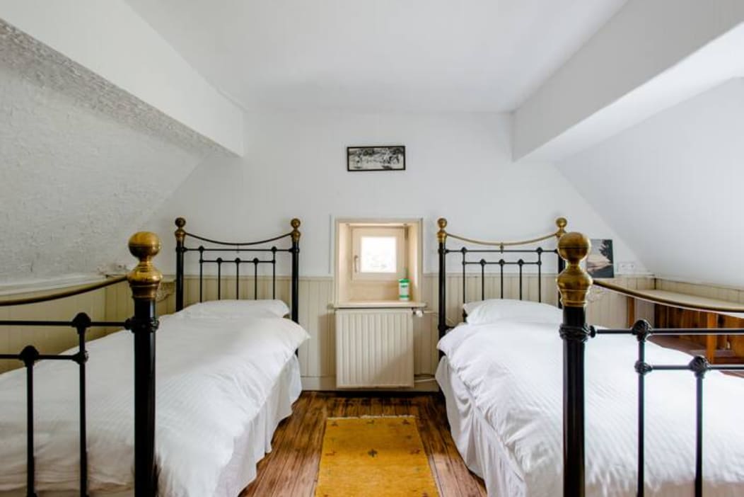 Biela izba: dve rovnaké mosadzné jednolôžka pod odkvapom. Najlepší výhľad v dome z malého okna „oeil de boeuf“!