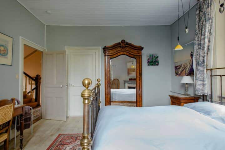The Blue Room: A spacious double room with direct access to the bathroom/toilet (shared). The antique brass bed is 140 cm wide. There is a shared walk-in closet and a small desk in the room, which has a view of the pool and the hill behind the house.