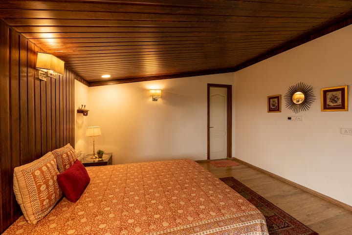 ห้องนอนยังคงธีมสีเอิร์ธโทนและองค์ประกอบตามธรรมชาติด้วยเตียงขนาดควีนไซส์ที่นุ่มสบายประดับประดาด้วยผ้าปูที่นอนออร์แกนิกนุ่มๆ