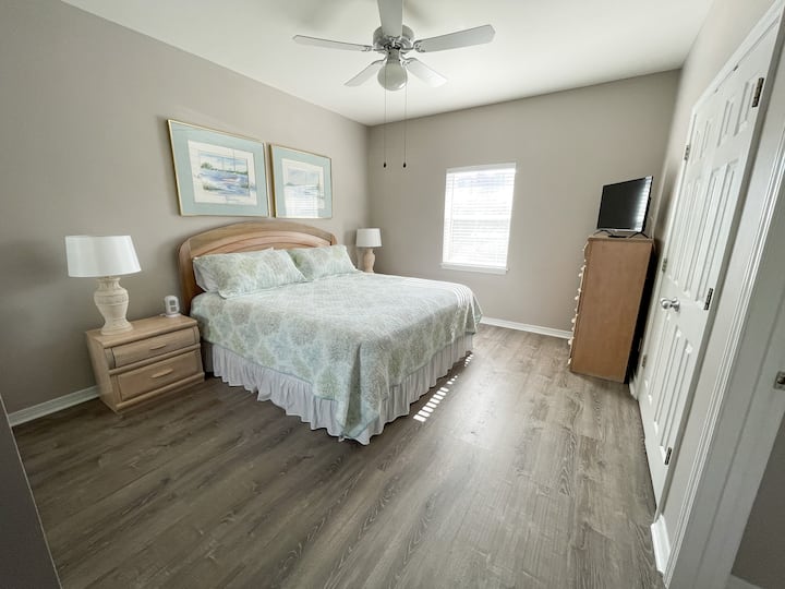 Master bedroom with a king bed, en suite bathroom, two closets, a smart TCL Roku TV, a dresser, two night stands, and a charging tower.