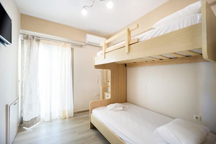 Ნათელი ორსართულიანი საძინებელი ტელევიზორითა და აივნით, ზედა სართულზე.