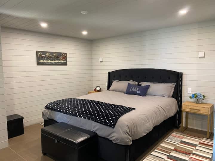 Niveau inférieur chambre principale au rez-de-chaussée avec grandes fenêtres et salle de bain attenante