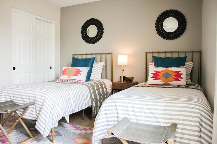 Stepping into bedroom number 4 - the Twin Room - with two twin beds and a bedside lamp to separate them. Each room has access to a closet and drawers to keep you organized and ready during your trip