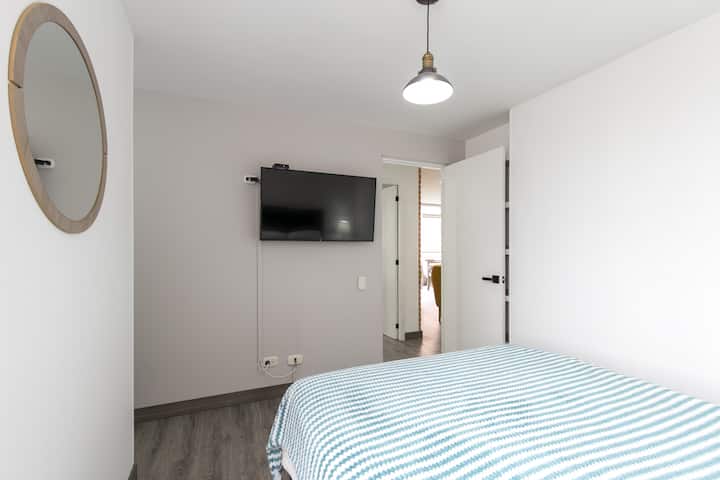 Dormitorio con cama doble con baño privado y TV.