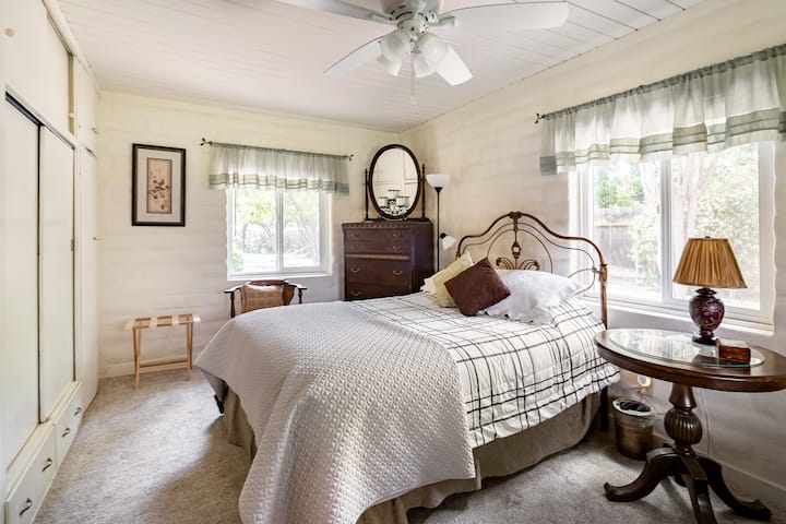 נוף לחדר שינה עם מיטת קווין סייז, שידה עתיקה ושידת לילה, ושפע של ארונות, ארונות ומגירות אחסון מובנות.