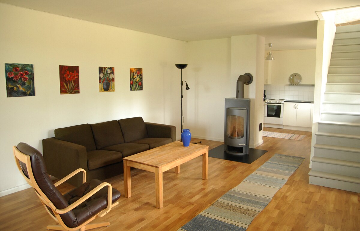 Large living room with sofa furniture, fireplace and kitchen in the distance. 