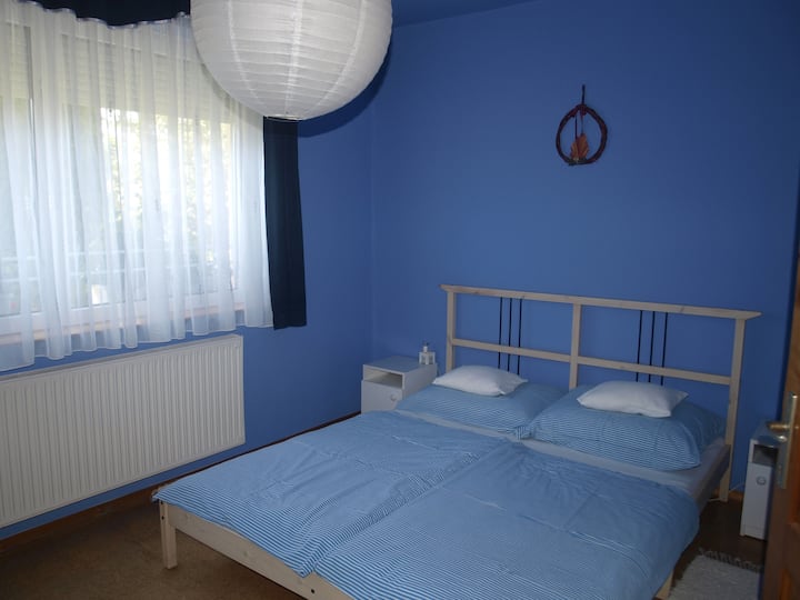 Een lichte slaapkamer beneden met een groot raam.
(Harmonie 1)