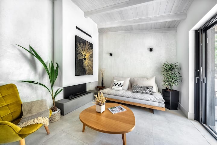 סלון פתוח המשלב ספה עם אח אקולוגית, כורסה נוחה ושידה בכניסה. הסלון עובר לפינת אוכל עם מטבח מאובזר, שולחן אוכל וגישה למרפסת. 